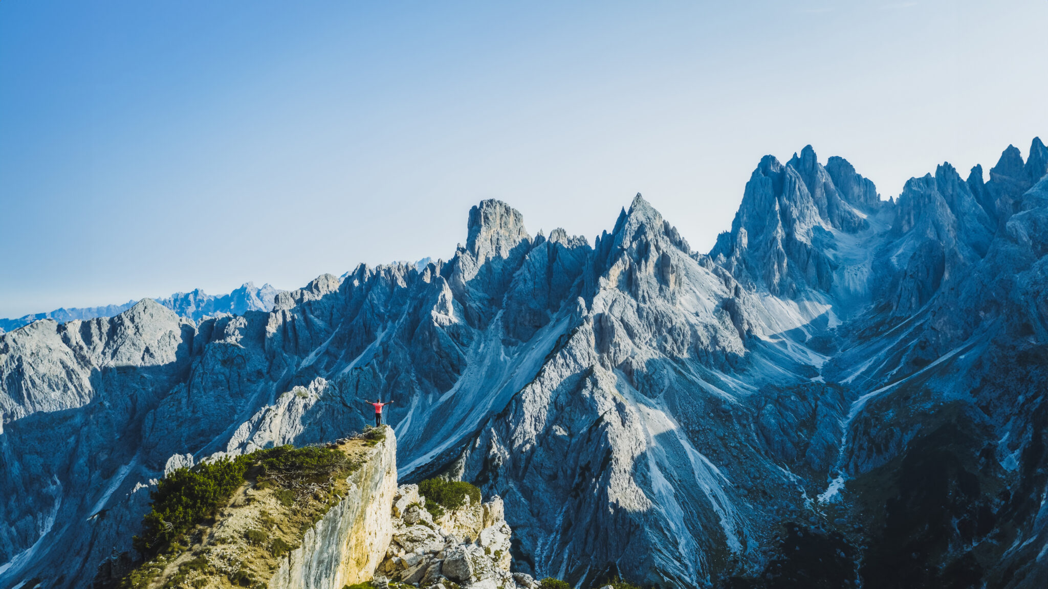 Aerial view of a man with raised hands enjoying Cadini di Misurina mountain peaks, Italian Alps, Dolomites, Italy, Europe.